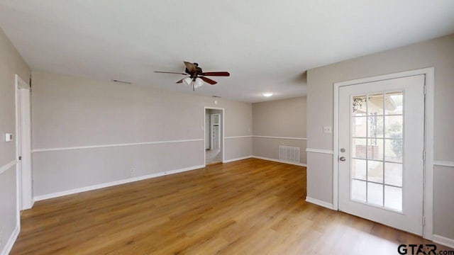empty room featuring baseboards, light wood-style floors, ceiling fan, and visible vents