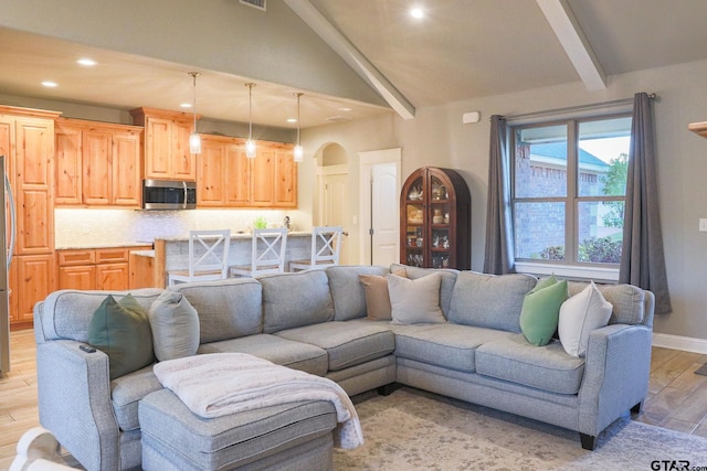 living room featuring vaulted ceiling with beams and light hardwood / wood-style flooring