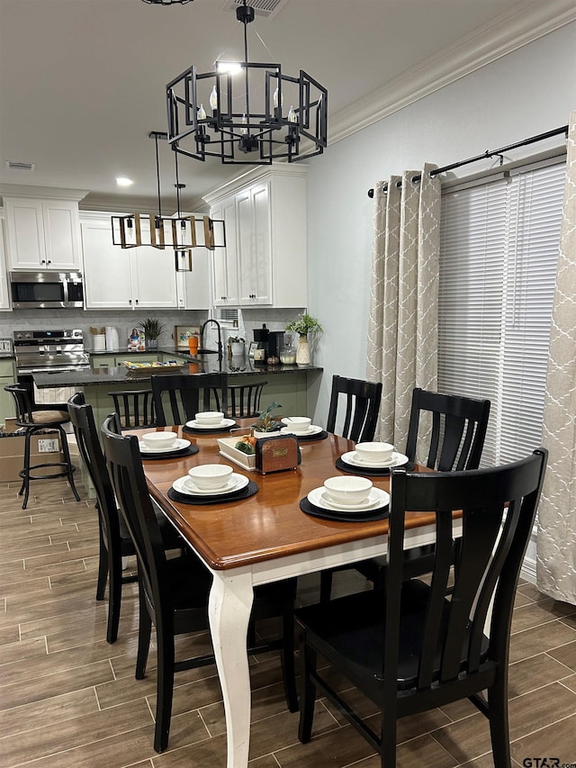 dining space featuring hardwood / wood-style flooring, an inviting chandelier, and crown molding