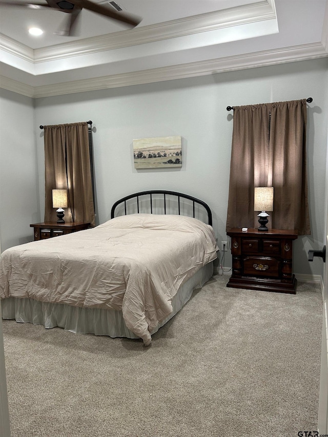 carpeted bedroom with ceiling fan, a tray ceiling, and ornamental molding