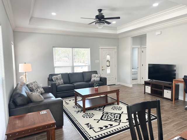 living room with hardwood / wood-style flooring, a tray ceiling, and ornamental molding