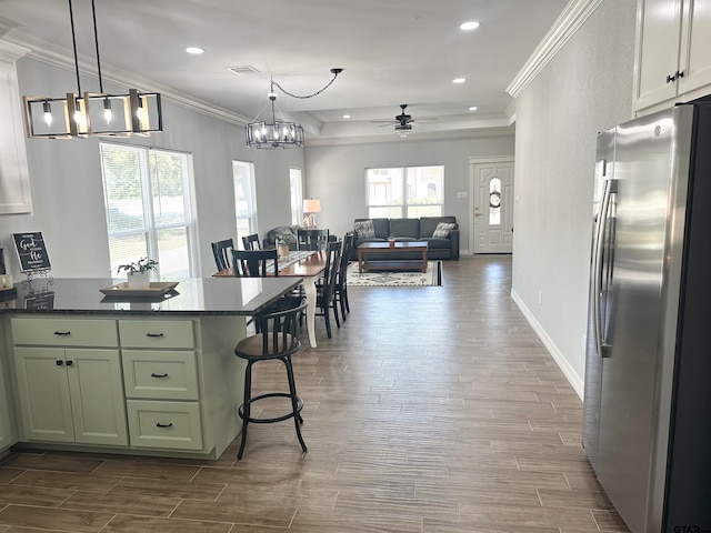 kitchen with dark wood-type flooring, a kitchen bar, a wealth of natural light, and stainless steel refrigerator