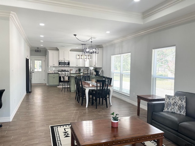 living room with light wood-type flooring, an inviting chandelier, and ornamental molding