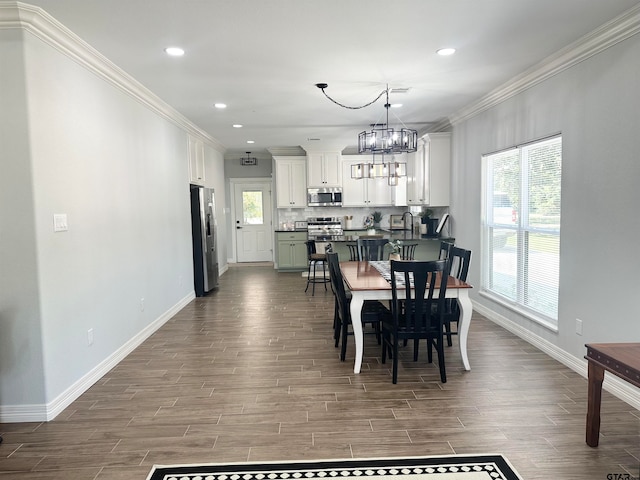 dining room featuring wood-type flooring, a notable chandelier, sink, and ornamental molding