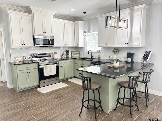 kitchen featuring pendant lighting, green cabinets, sink, white cabinetry, and appliances with stainless steel finishes