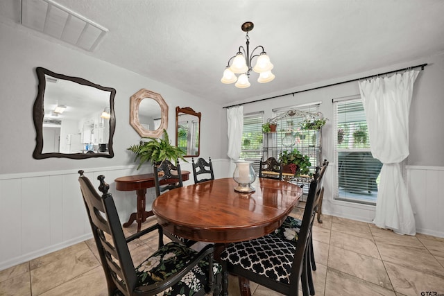 tiled dining space featuring a notable chandelier and a textured ceiling