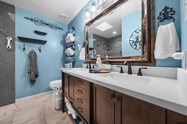 bathroom with vanity, a textured ceiling, toilet, a skylight, and a shower with shower door