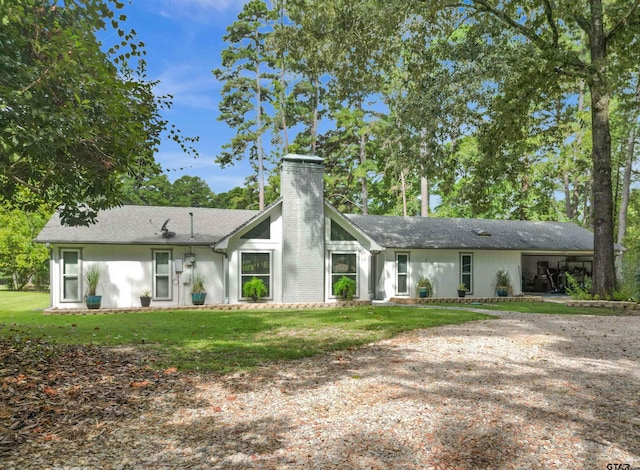 rear view of house featuring a lawn and a carport