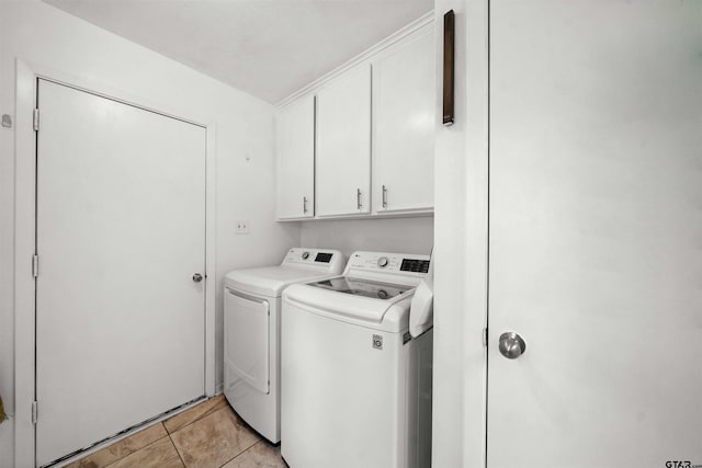 laundry room featuring washing machine and clothes dryer, light tile patterned flooring, and cabinets