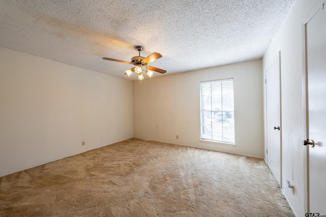 spare room with a ceiling fan, light colored carpet, and a textured ceiling