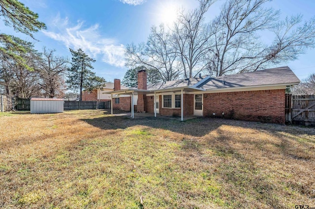 back of property with brick siding, a yard, a storage shed, a fenced backyard, and an outdoor structure