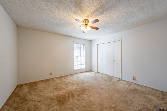 unfurnished bedroom with a textured ceiling, carpet floors, a closet, and ceiling fan