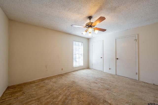 unfurnished bedroom with carpet floors, two closets, a ceiling fan, and a textured ceiling