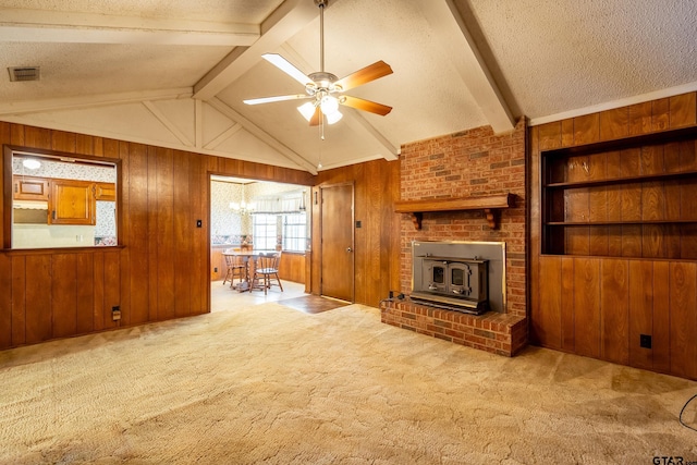 unfurnished living room featuring vaulted ceiling with beams, a textured ceiling, carpet floors, wood walls, and ceiling fan with notable chandelier