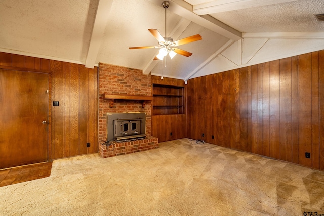 unfurnished living room with built in shelves, lofted ceiling with beams, wood walls, a textured ceiling, and ceiling fan