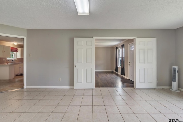 spare room with light tile patterned flooring, a healthy amount of sunlight, and a textured ceiling