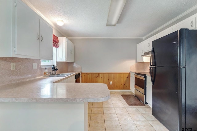 kitchen featuring black appliances, white cabinets, sink, wooden walls, and kitchen peninsula