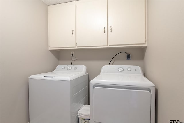 laundry room featuring separate washer and dryer, cabinets, and a textured ceiling