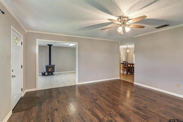 spare room featuring a textured ceiling, ceiling fan, crown molding, hardwood / wood-style floors, and a wood stove