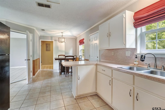 kitchen with pendant lighting, sink, ornamental molding, a textured ceiling, and white cabinetry