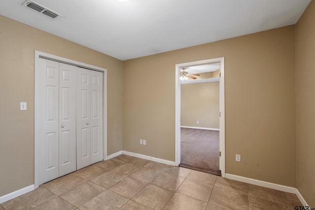 unfurnished bedroom with light tile patterned floors, baseboards, visible vents, and a closet