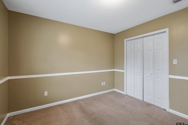 unfurnished bedroom with baseboards, carpet floors, a closet, and visible vents