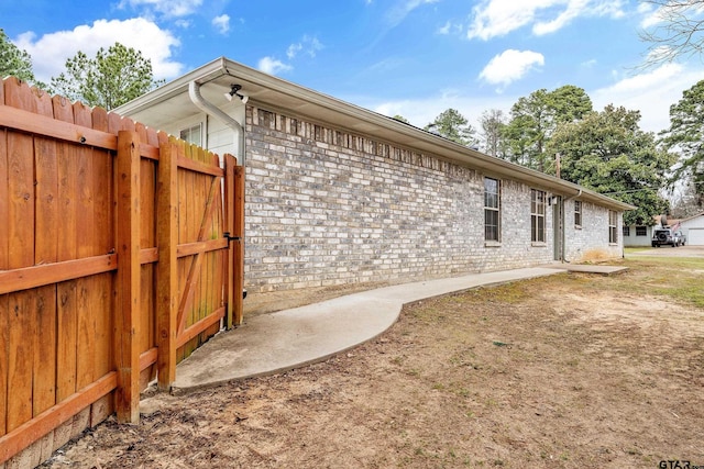 view of home's exterior featuring brick siding and fence