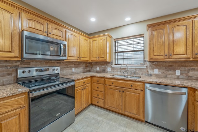 kitchen featuring a sink, light stone counters, tasteful backsplash, recessed lighting, and appliances with stainless steel finishes