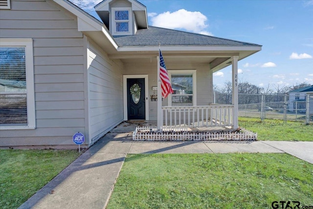 view of exterior entry with a porch and a lawn