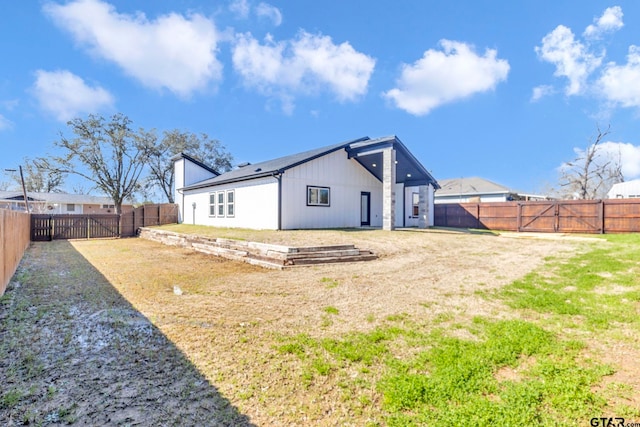 rear view of house with a yard and a fenced backyard