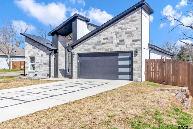 view of front facade with stone siding, concrete driveway, a garage, and fence