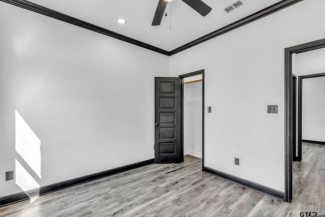 spare room featuring visible vents, ornamental molding, a ceiling fan, wood finished floors, and baseboards