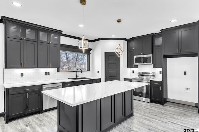 kitchen featuring ornamental molding, a sink, a center island, stainless steel appliances, and glass insert cabinets