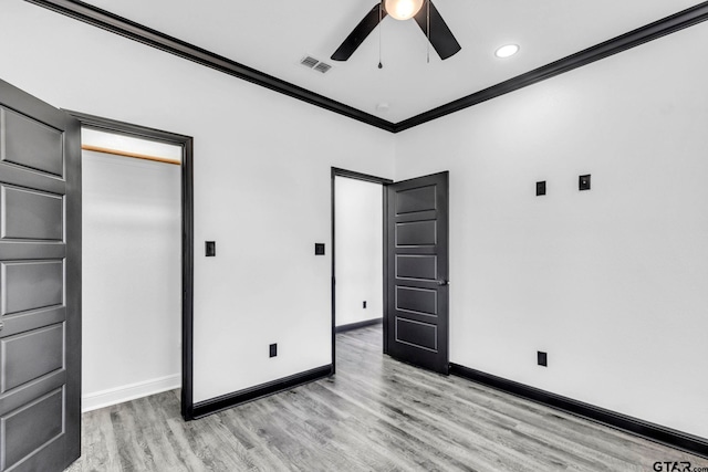 unfurnished bedroom with visible vents, light wood-style flooring, crown molding, and baseboards