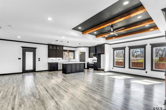 unfurnished living room with beamed ceiling, baseboards, wood finished floors, and crown molding