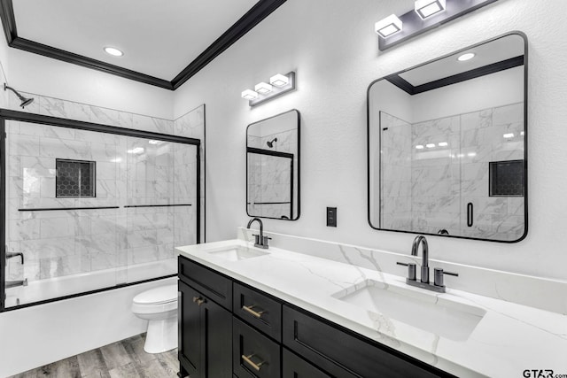 bathroom with crown molding, toilet, wood finished floors, and a sink