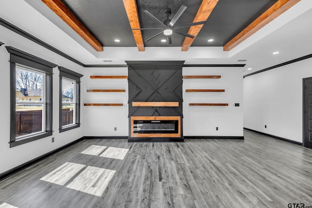 unfurnished living room with beam ceiling, a fireplace, baseboards, and wood finished floors