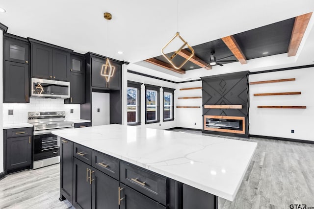 kitchen featuring beam ceiling, light wood-style flooring, a ceiling fan, tasteful backsplash, and stainless steel appliances