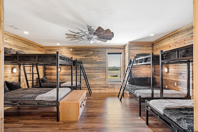 bedroom featuring wooden walls, dark hardwood / wood-style floors, and ceiling fan