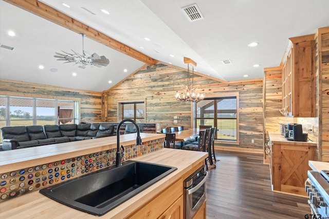 kitchen with wood walls, hanging light fixtures, vaulted ceiling with beams, and appliances with stainless steel finishes