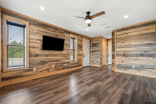 unfurnished living room featuring dark wood-type flooring, wooden walls, and ceiling fan