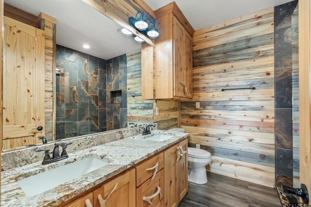 bathroom with toilet, wood walls, vanity, and hardwood / wood-style flooring