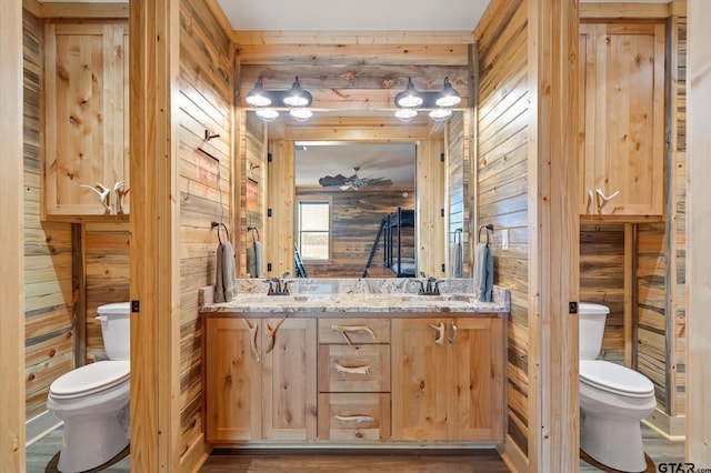 bathroom featuring wood walls, vanity, and toilet