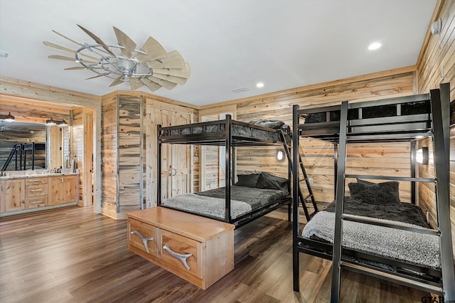 bedroom with dark wood-type flooring, wooden walls, and ceiling fan