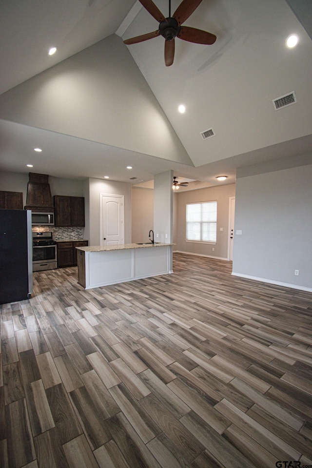 unfurnished living room with a ceiling fan, visible vents, baseboards, and wood finished floors