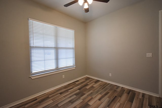 spare room featuring dark wood-style floors, ceiling fan, and baseboards