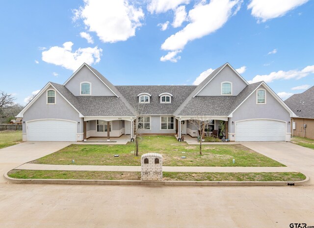 view of front of property featuring a front yard, covered porch, driveway, and stucco siding