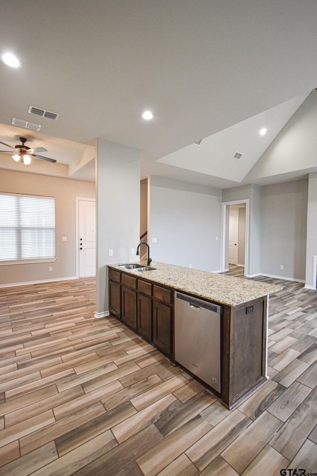 kitchen featuring wood finish floors, a sink, open floor plan, light stone countertops, and dishwasher