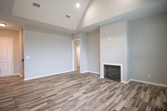 unfurnished living room with baseboards, a fireplace, visible vents, and wood finished floors