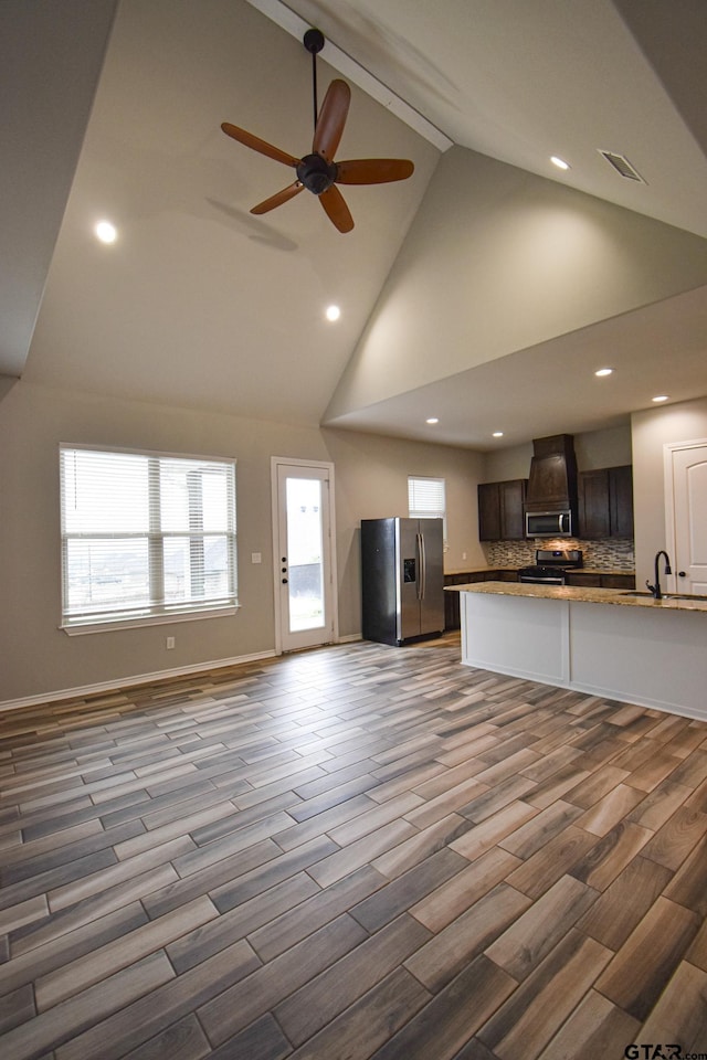 kitchen with stainless steel appliances, light countertops, open floor plan, a sink, and dark brown cabinets